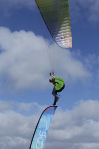 Acro pilot Renan Morales stands on a flag while paragliding